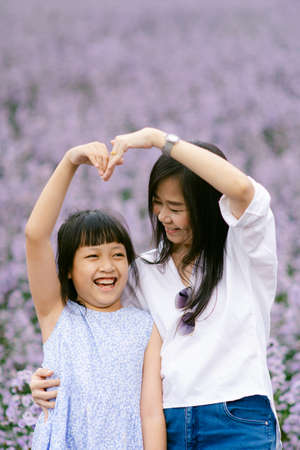 Happy mother and daughter smiling in a beautiful flowers field.Concept of mother dayの写真素材