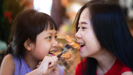 Asian mother and daughter eating sausage with happiness.Concept of Mother's Dayの写真素材
