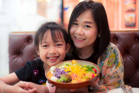 Happy daughter and mother holding a vegetable salad in the restaurant.Concept of mother dayの写真素材