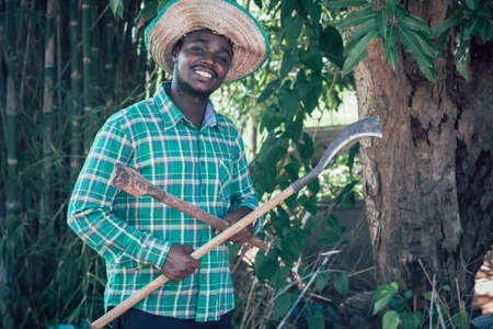 African farmer holding a knife and spade in farm.Agriculture or cultivation conceptの写真素材