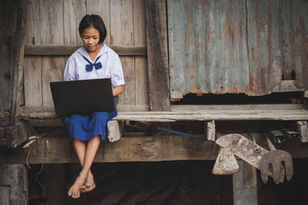 Asian uniform student girl using computer laptop during the lock-down period at homeの写真素材