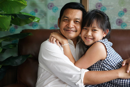 Adorable asian daughter hugging loving father with love and tenderness.Concept of fathers dayの写真素材