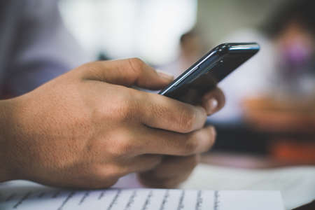 Students are test exam and study online by using smartphone and wearing protective face mask in classroomの写真素材