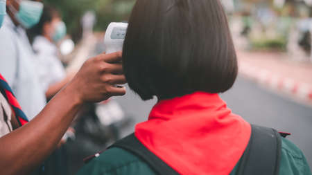 Students standing for a temperature test to prevent infectious Covid-19 diseaseの写真素材