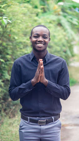 A charming, friendly african man who stands smiling and shows sincere respect