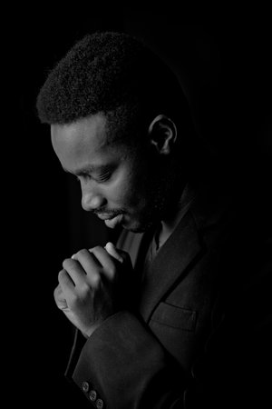African man praying for god in the dark room.Low key lighting styleの写真素材