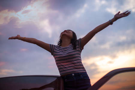 Freedom asian woman feeling free raised his hands to top with the sunset in backgroundの写真素材