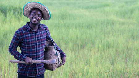 African farmer with hat holding a shovel in the organic rice field.Agriculture or cultivation conceptの写真素材