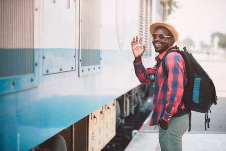 African male traveler with hat and sunglasses waiting for the train on railway station.Adventure...