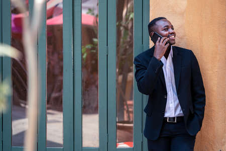 A handsome african businessman standing side of  the windows while talking on his phone