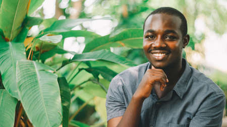 A charming, friendly african man who stands smiling with the green nature background