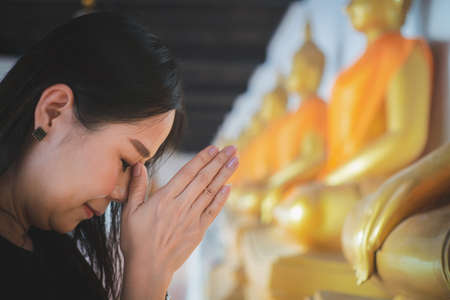 Asian woman pays homage to the Buddha statue with respect and faithの写真素材
