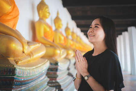 Asian woman pays homage to the Buddha statue with respect and faithの写真素材