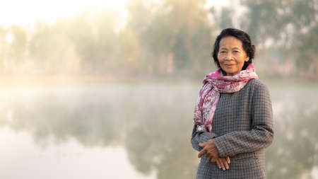 Happy asian elderly senior smile with the nature lake in background, Lifestyle of Asian old women conceptの写真素材