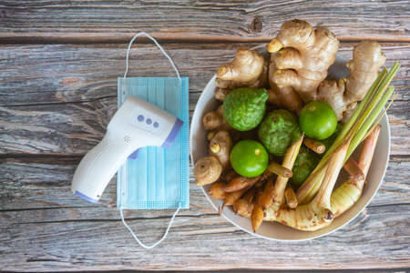 Thai herbs include many types such as ginger, galangal, lemongrass, kaffir lime, lemon with thermometer and face mask. Concept of herbal  for antiviral and immune to the bodyの写真素材