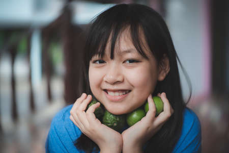 Asian child girl holding the lime lemon and   bergamot with smile and happy, Concept of herbal  for antiviral and immune to the bodyの写真素材