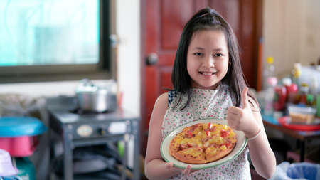 Happy little girl preparing homemade pizza in the home kitchenの写真素材