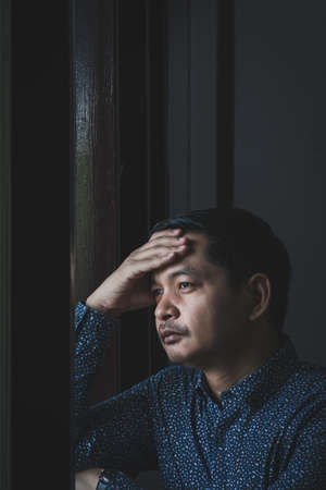 Sad man thinking and looking out the windowの写真素材
