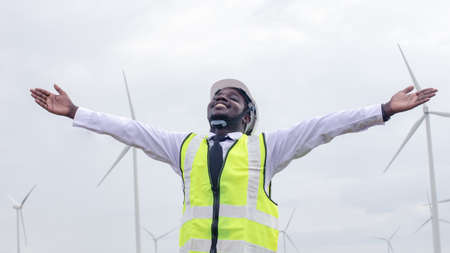 African male engineers working on site with wind turbine propeller and clear blue sky on the background. Alternative energy, environmental friendly for the future. clean energy innovationの写真素材