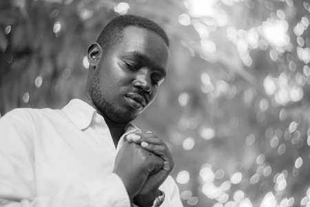 African man praying for thank god with light flare and beautiful bokeh in black and white styleの写真素材