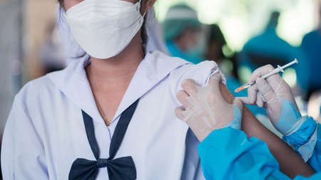 Doctor is vaccinating students in uniform to prevent virusの写真素材