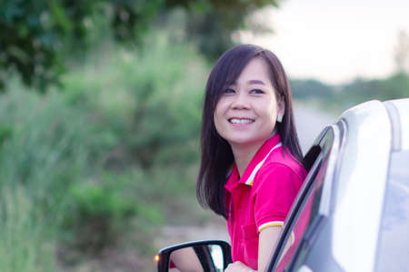 Happy woman looking out of car window with smile and relaxの写真素材