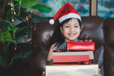 Happy smile girl in a Santa hat wearing medical face mask with Christmas gift boxesの写真素材