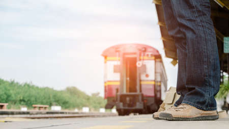 The legs of an adventurer wearing sneakers waiting for the train.Travel and adventure concept