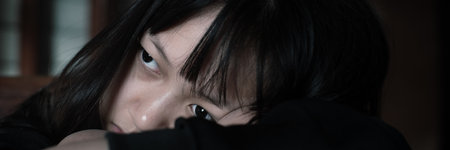 Sad lonely little girl crying while sitting in dark room with an attitude of sadness.Concept of depression or domestic violence childの写真素材