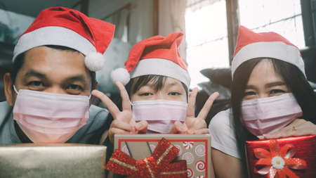 Christmas happy family wearing face mask and hugging gift box present at home