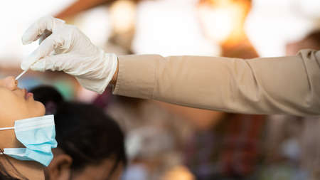 Uniform Teachers are screening students for COVID-19 prevention in schools. Teacher swab Corona virus testing by Rapid Antigen Test kit for students with a cotton nasal swabの写真素材