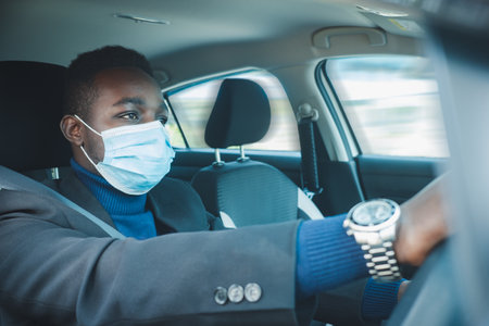 African business man driving a car with wearing medical mask for protection corona virus or Covid-19の写真素材