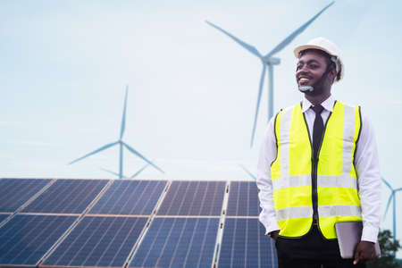 African engineer manager stand holding tablet front solar photovoltaic and wind turbines generating electricity power station. 
Concept of sustainability development by alternative energyの写真素材