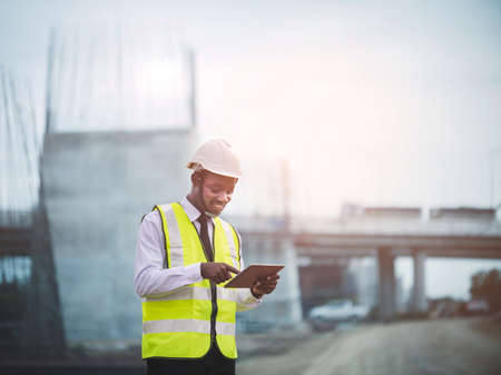 African civil engineer working with use tablet for control the road rebuilding and inspect the construction site with roller compactor machine on a roadの写真素材