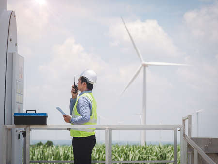 Engineer man is using a tablet to control and monitor the operation of a wind turbine in the...