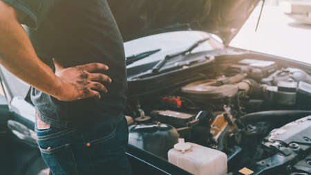 A stressed man looks and analysis to repairing a faulty engine in garageの写真素材