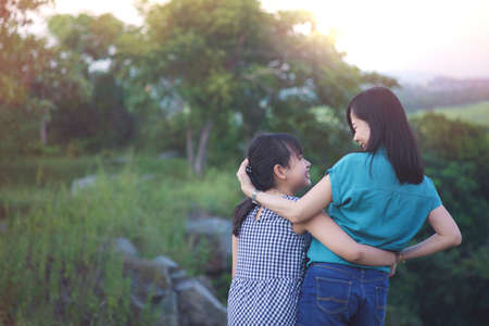 Mother and daughter are hugging and having fun outdoor in green nature with sunset.Concept of mother's dayの写真素材