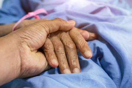 Close-up of child holding mother's hand while sick, son's hand touching elderly woman in hospitalの写真素材