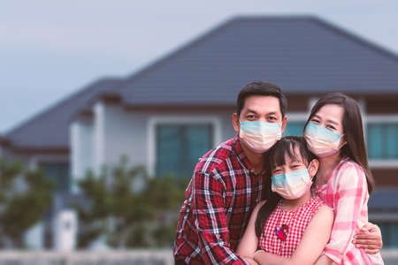 Family wearing a face mask to prevent virus Covid-19 out house .Father mother and daughter hugging for protect corona virus at homeの写真素材