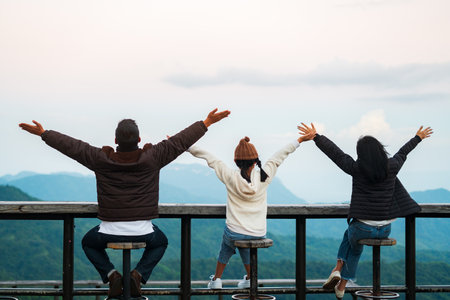 Happy family, featuring father, mother and daughter, raising their arms to convey Freedom with a view of the mountains in the backgroundの写真素材