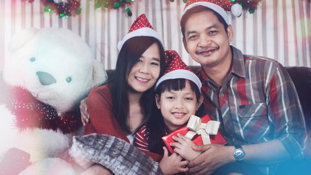 Merry Christmas and Happy Holidays! Cheerful family exchanging gifts, Father mother and gaughter having fun in the house with presents in the room at homeの写真素材