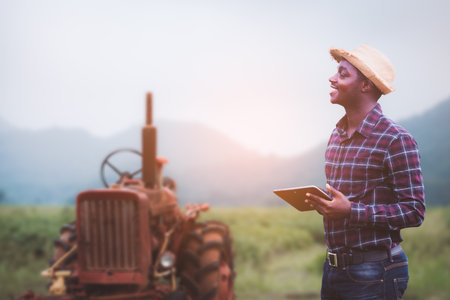 Success african male farmer in checkered shirt and straw hat holding digital tablet with smile and...