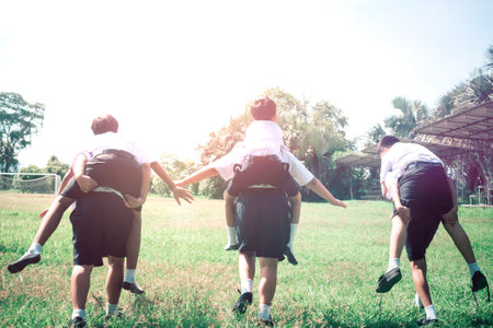 Students were running around and riding on their backs happily in the grass.Concept of Best Friendsの写真素材