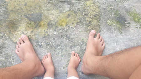 Close up of man and baby feet on cement floor, closeup of bare feet and toesの写真素材