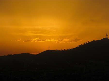Sunset over the hills of Barcelona with yellow skyの写真素材