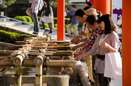 People washing hands at a Tsukubai in front of the Inari Shrine in Kyoto in order to purify themselves by the ritual washingのeditorial素材