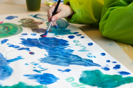 Child painting with an paint brush and water colors on paperの写真素材