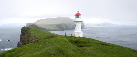 Lighthouse on Mykines Holmur with rocks, green, grass and beautiful landscape of the Faroe Islandsの写真素材
