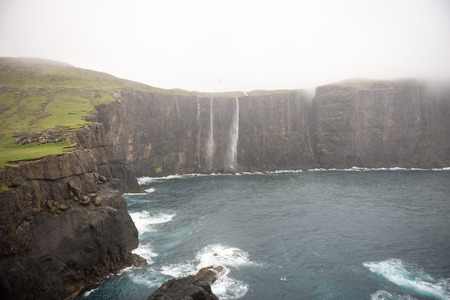 Typical landscape on the Faroe Islands, with cliffs and water fallの写真素材
