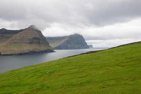 Typical landscape on the Faroe Islands, with green grass and rocks close to Vidareidiの写真素材